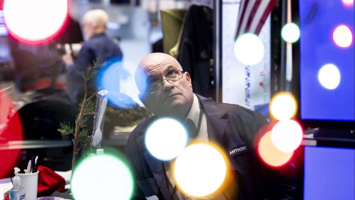 A trader works on the floor as news of the Federal Reserve rate cut decision shows on a TV at the New York Stock Exchange